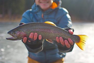 a man holding a rainbow trout caught fishing in the Black Hills